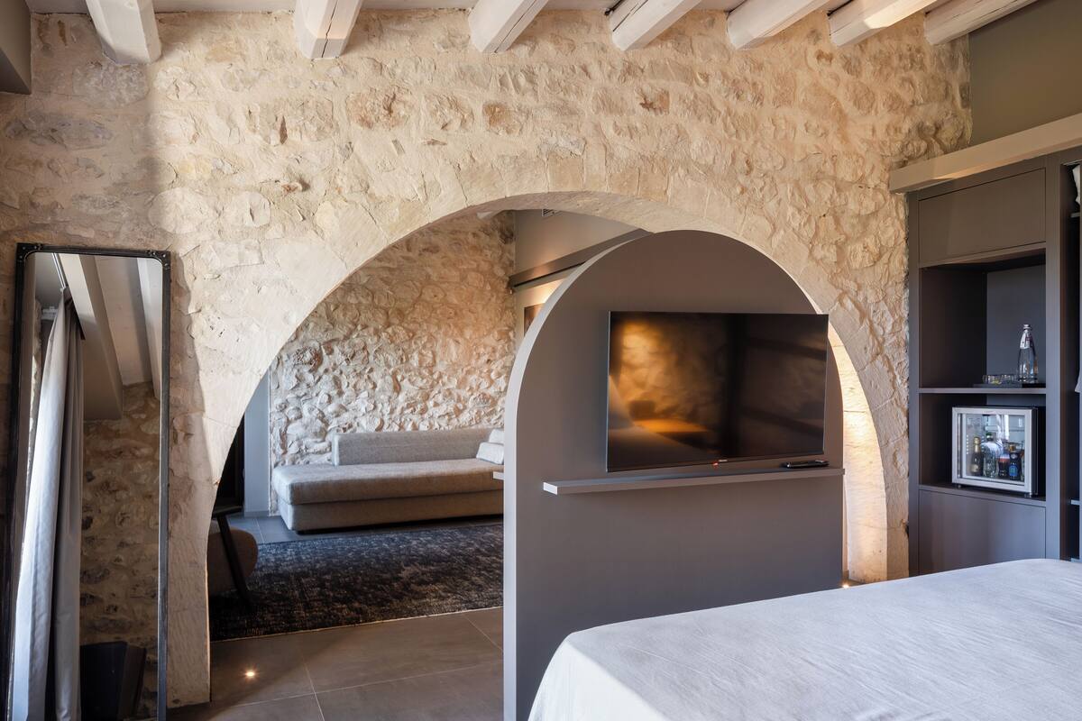 Une chambre moderne avec un mur en pierre, une cheminée, un canapé et un lit.