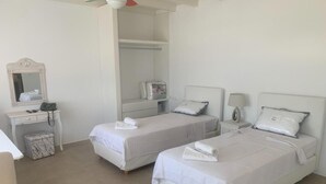 Una habitación de hotel con dos camas, un escritorio, una silla, un armario y un espejo.
