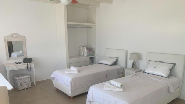 Une chambre d’hôtel avec deux lits, un bureau, une chaise, une armoire et un miroir.