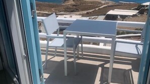 Balcón con mesa y sillas con vista a un paisaje costero.