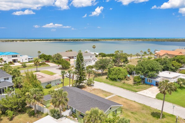 A residential area with houses, a road, and a body of water in the background.