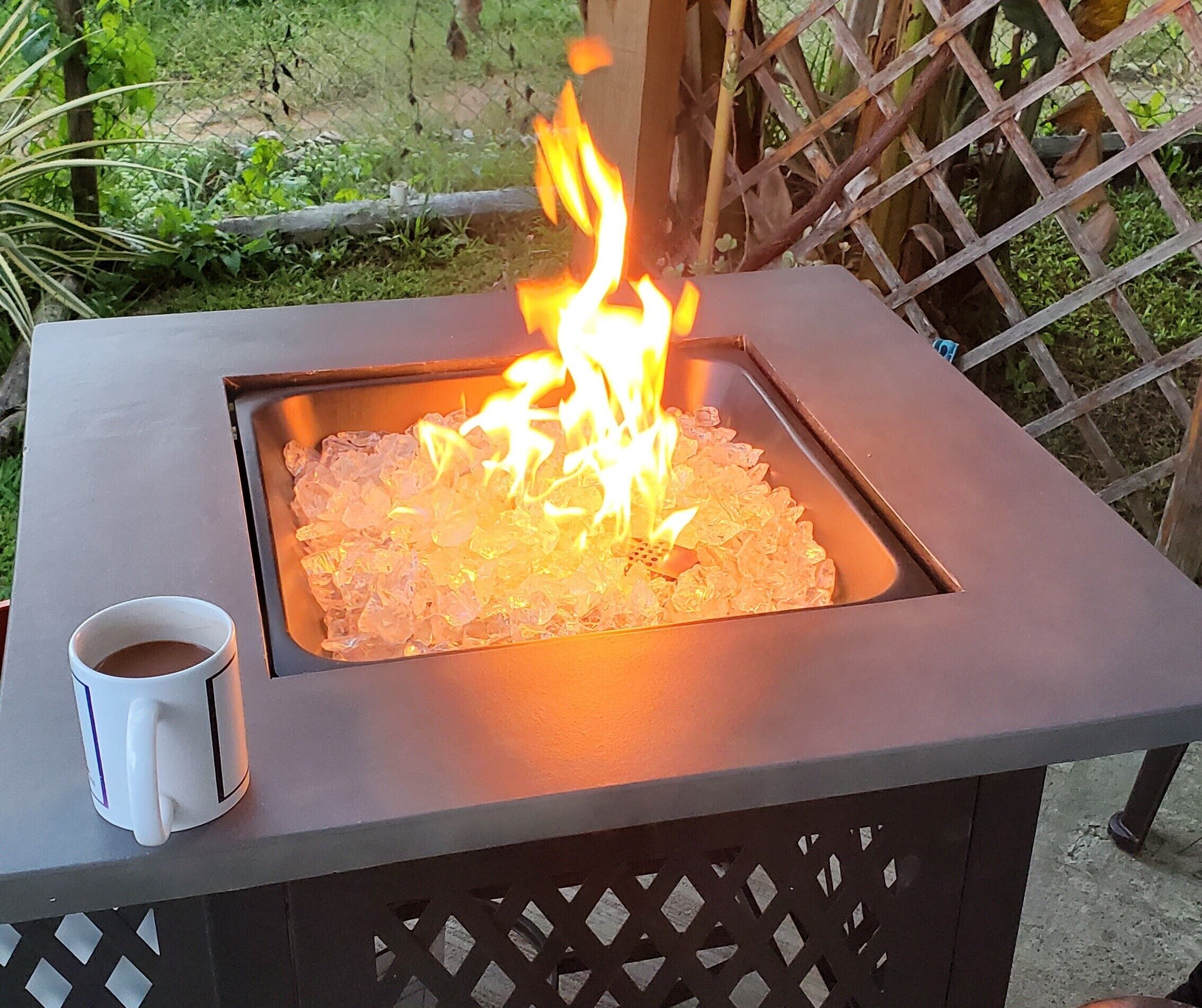 A square fire pit with a white mug on the left.