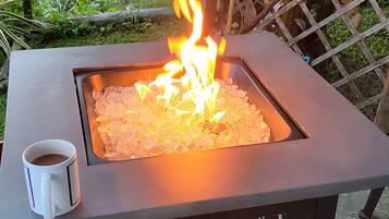 A square fire pit with a white mug on the left.