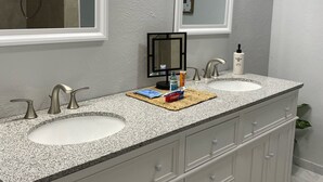 Une salle de bain avec deux lavabos, un grand miroir et une douche.