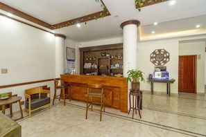A hotel lobby with a reception desk, seating area, and a decorative wall. - Xianyan Hotel (Yueqing)
