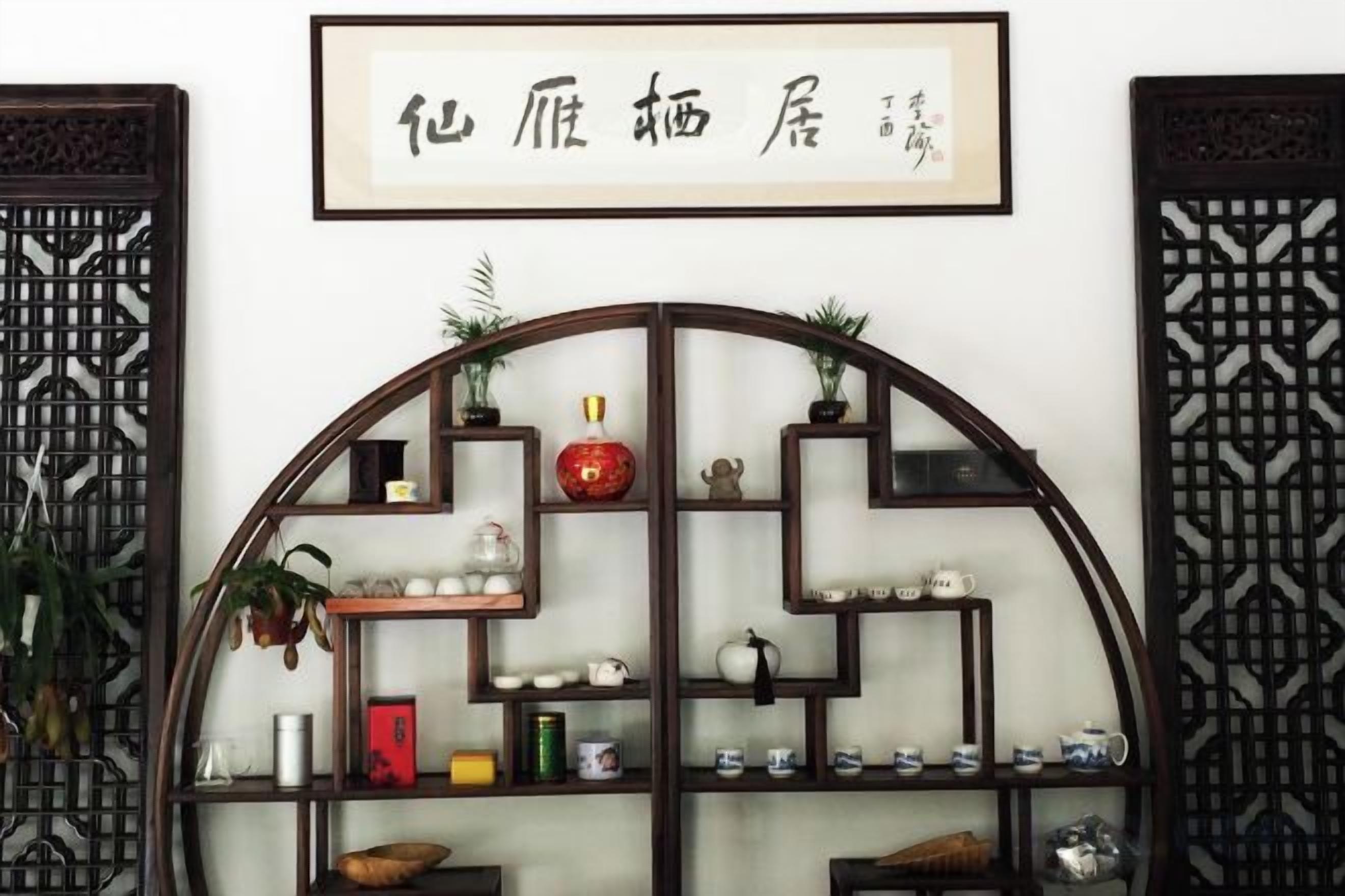 A traditional Chinese-style shelf with various decorative items and a framed calligraphy piece above it.