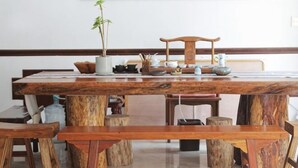 A wooden dining table with benches, surrounded by wooden stools. - Xianyan Hotel (Yueqing)