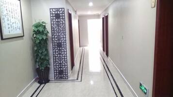 A corridor with a decorative screen, a potted plant, and a sign indicating a direction.