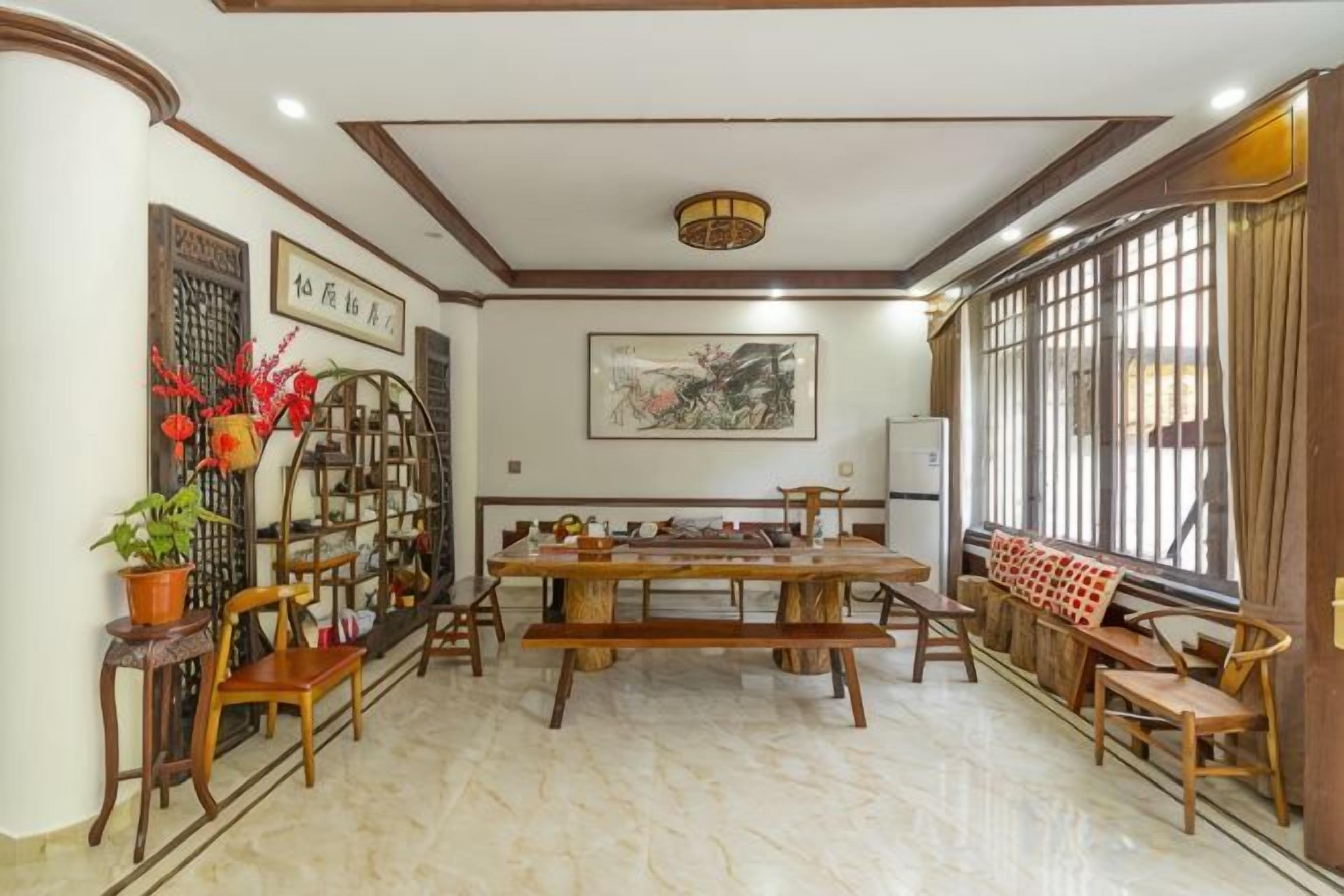 A traditional dining area with a wooden table, chairs, and a decorative screen.