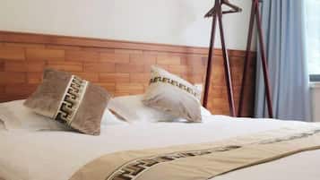 A bed with a wooden headboard, two pillows with a geometric pattern, and a hanging wooden rack.