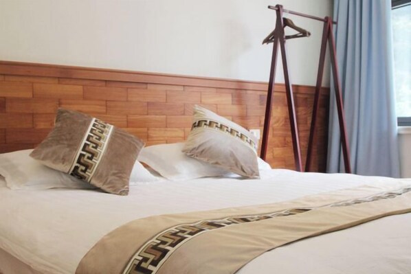 Una cama con cabecera de madera, dos almohadas con un diseño geométrico y un perchero de madera colgante.