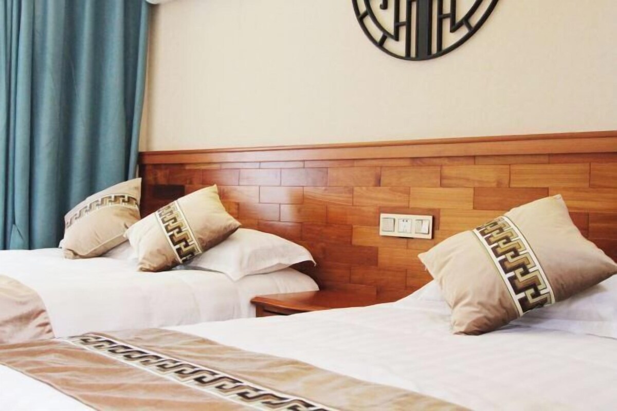 Habitación de hotel con dos camas, cada una con almohadas a juego y un cabecero de diseño geométrico.