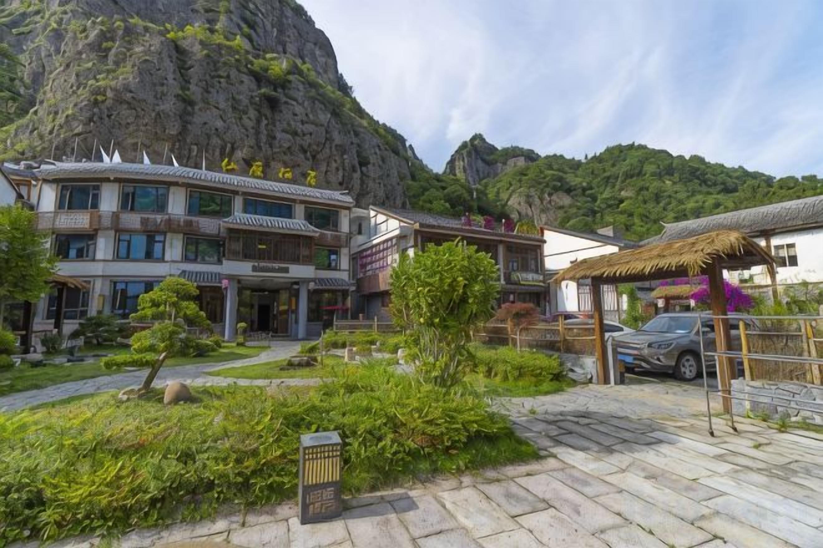 Un bâtiment traditionnel à étages, doté d’une cour intérieure agrémentée de plantes et surplombant un paysage montagneux.