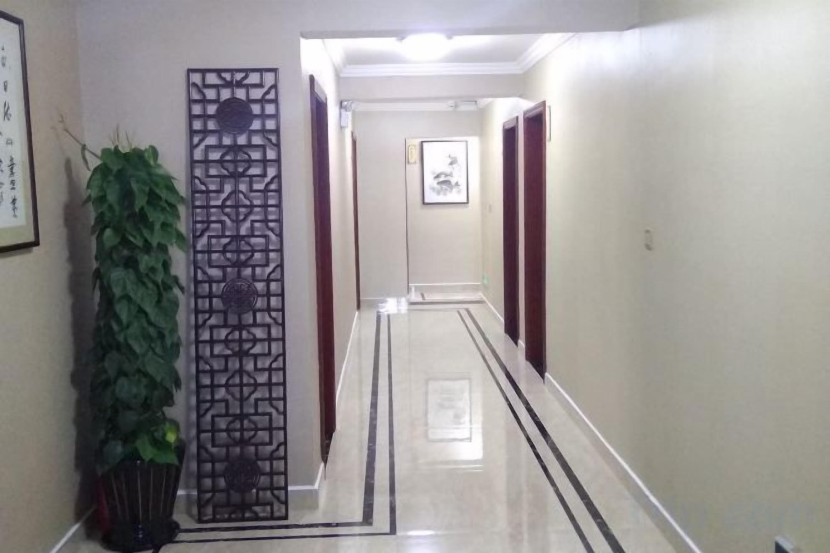 A hallway with a decorative screen, a potted plant, and a framed picture on the wall.