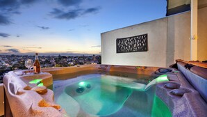 A hot tub with a city view, a bottle of wine, and a decorative wall panel.