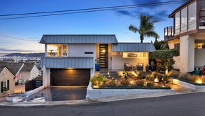 A modern two-story house with a garage, a well-lit entrance, and a landscaped garden.