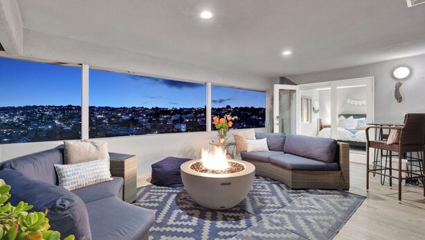 A modern living room with a fire pit, comfortable seating, and a city view.