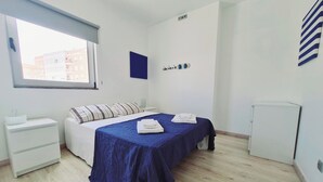 Une chambre à coucher comprenant un lit, une table de chevet, une commode, une fenêtre et un radiateur fixé au mur.