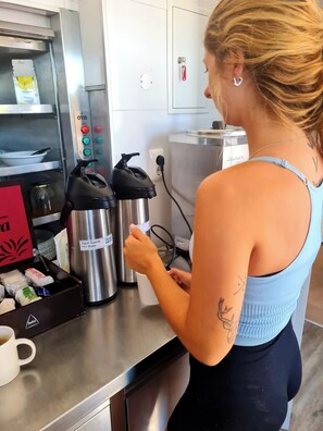 Une personne, dans une cuisine, prépare une boisson à l’aide d’une machine à café.