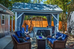 Un espace extérieur aménagé, abrité et doté de mobilier en osier, ainsi qu’un jacuzzi.