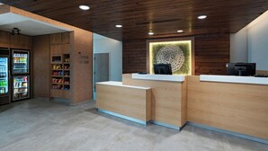 A reception area with wooden paneling, a counter, and a vending machine. - Fairfield Inn & Suites by Marriott Fort Worth Alliance Airport (Fort Worth)