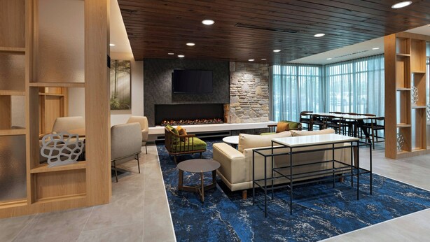 A modern lounge area with a fireplace, seating, and a large window providing natural light. - Fairfield Inn & Suites by Marriott Fort Worth Alliance Airport (Fort Worth)