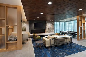 A modern lounge area with a fireplace, seating, and a large window providing natural light. - Fairfield Inn & Suites by Marriott Fort Worth Alliance Airport (Fort Worth)