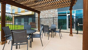 An outdoor patio with a pergola, outdoor seating, and a stone building in the background. - Fairfield Inn & Suites by Marriott Fort Worth Alliance Airport (Fort Worth)