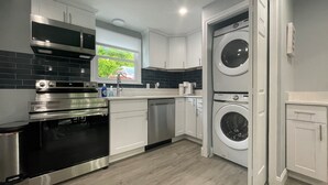 A modern kitchen with stainless steel appliances, white cabinetry, and a built-in washer and dryer. - New, Modern 2 BR Apartment near Hospitals | HBHS (Worcester)