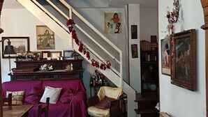 A cozy living room with a staircase, a dining area, and a fireplace.