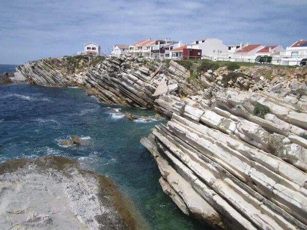 Une zone côtière caractérisée par des falaises rocheuses et des maisons aux toits rouges.