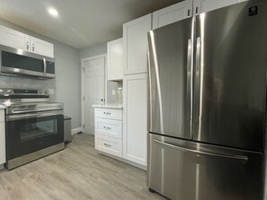 Uma cozinha moderna com eletrodomésticos de aço inoxidável, incluindo geladeira, forno e micro-ondas.