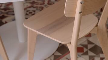 A wooden chair with a high backrest and a woven basket on a white table.