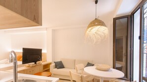 A modern kitchen with a dining area, a sofa, and a TV.
