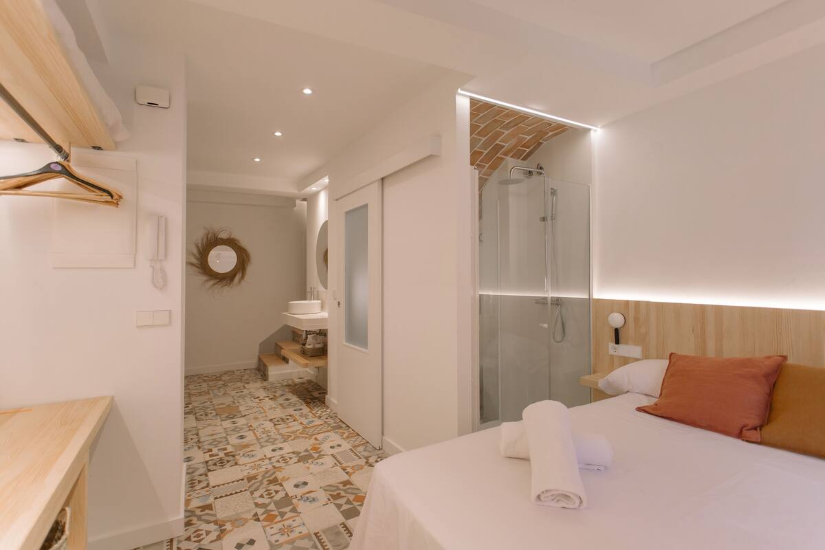 Une chambre d’hôtel moderne équipée d’un lit, d’une douche, d’une salle de bain et d’un couloir menant à une autre chambre.