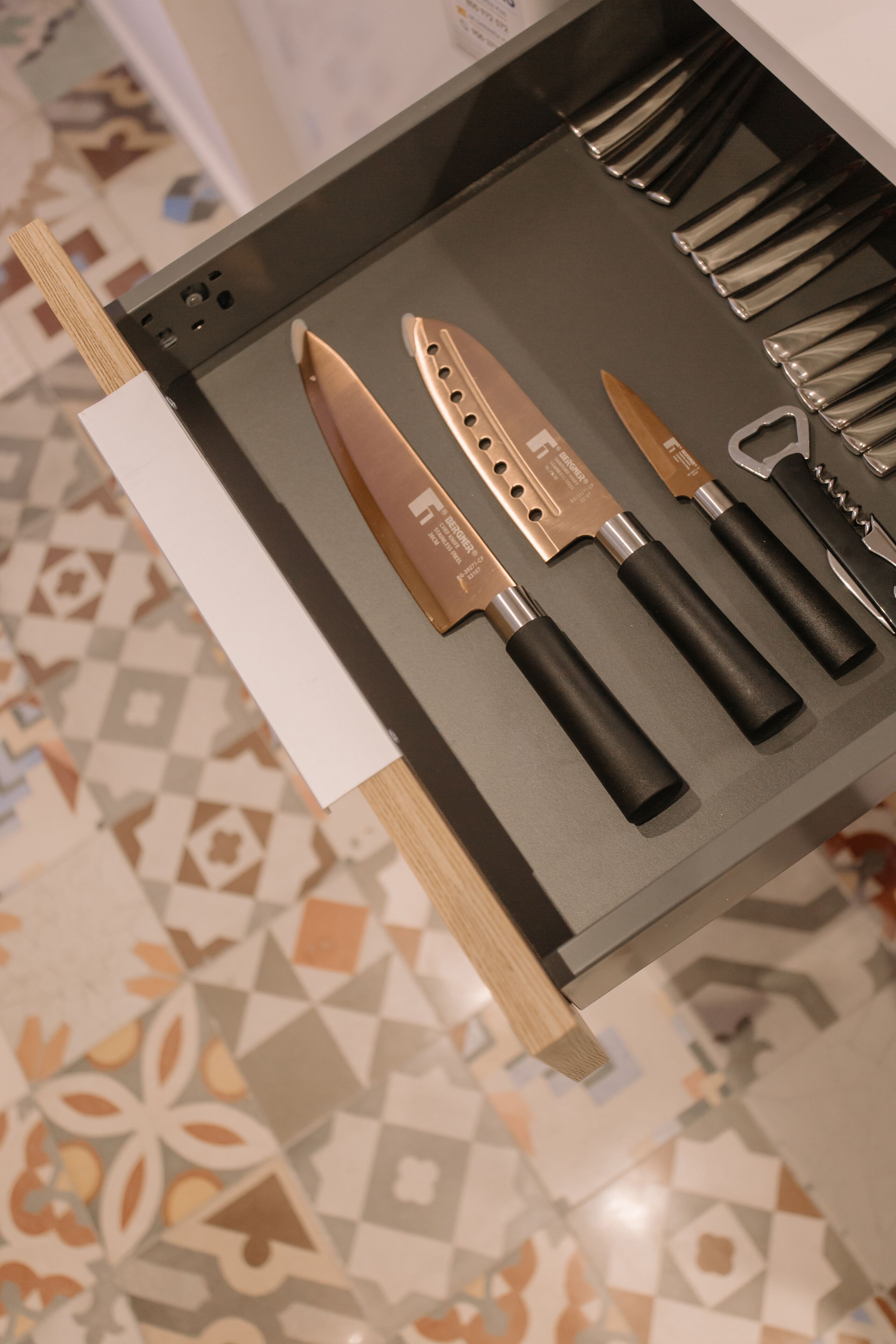 A drawer with various kitchen knives and utensils.