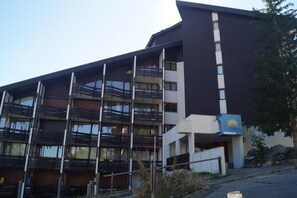 Een meerlaags gebouw met balkons, een bordje dat een spa aangeeft, en een stenen structuur in de buurt.