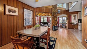 Un intérieur en bois comprenant une table à manger, des chaises, une cheminée et un pilier en pierre.