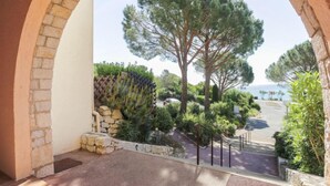 A balcony with a stone wall, a view of a pine tree, and a paved area with a railing. - La Gaillarde by Interhome (Les Issambres)