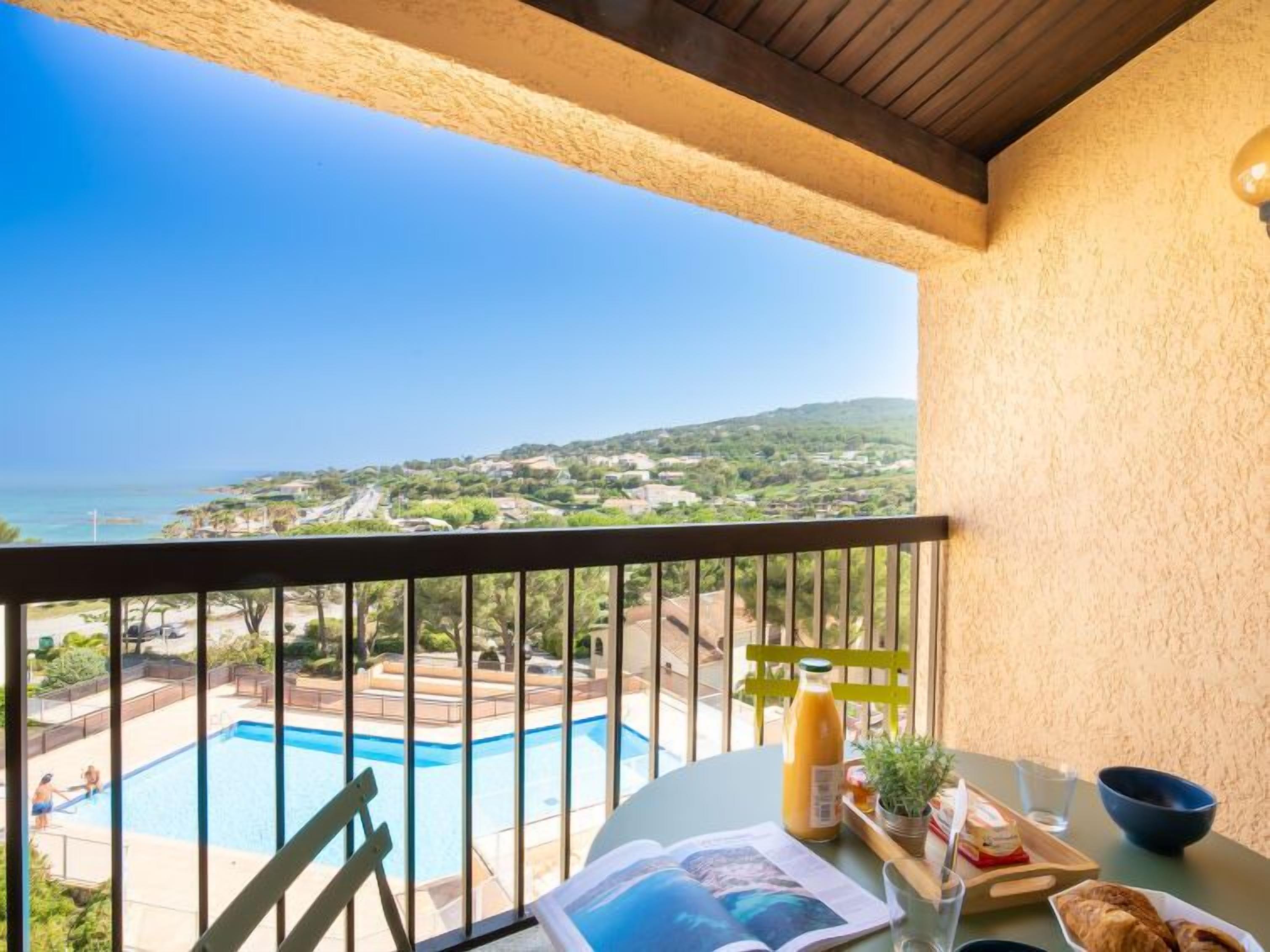 Un balcone con vista su una piscina e un paesaggio lontano.