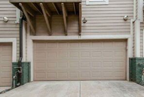 A garage door with a number "10" on it, a covered entryway, and a green brick wall.
