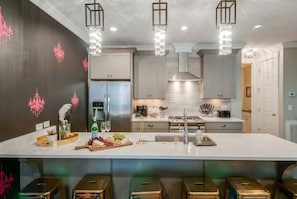A modern kitchen with a large island, stainless steel appliances, and pendant lighting.