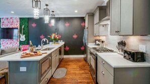 A modern kitchen with a central island, stainless steel appliances, and a backsplash with decorative elements. - Nashville getaway: happy hour bar, disco theme room, bunk room, sleeps 12 (Nashville)