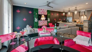 A modern living room with a black and pink color scheme, a glass coffee table, and a sofa. - Nashville getaway: happy hour bar, disco theme room, bunk room, sleeps 12 (Nashville)