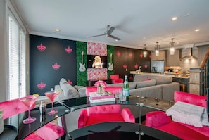A modern living room with a black and pink color scheme, a glass coffee table, and a sofa.