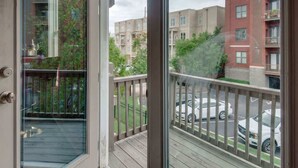 A view from a balcony with a wooden deck, overlooking a parking area and multi-story buildings. - Nashville getaway: happy hour bar, disco theme room, bunk room, sleeps 12 (Nashville)
