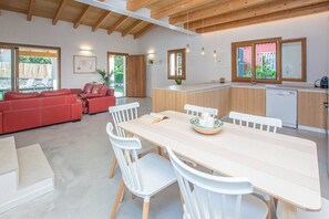 A modern kitchen with a wooden countertop, white chairs, and a dining table.