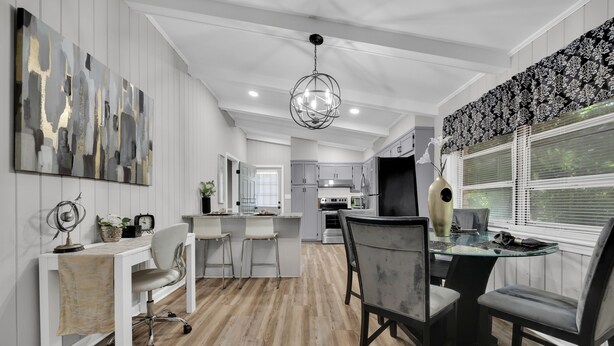 A modern kitchen with white cabinetry, a central island, and a dining area with a glass table and chairs.