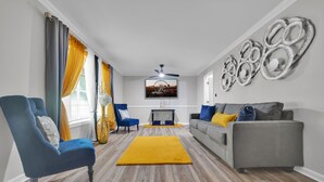 A living room with a grey sofa, a blue armchair, and a yellow rug.