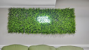 A room with a green wall and a neon sign that reads "Good Vibes".